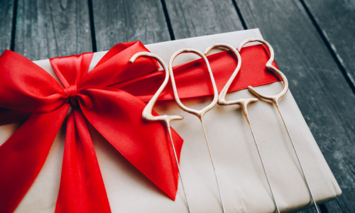 An image of a holiday concept with 2023 decorations and a gift box with a red bow on a wooden table 